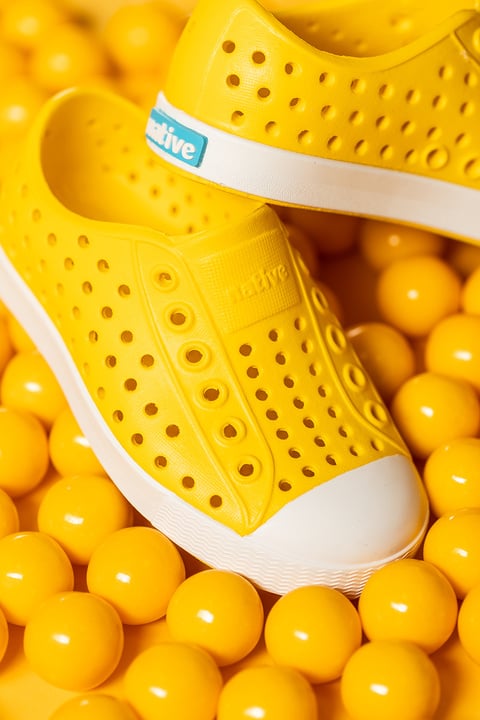 Bright yellow shoes photographed among matching yellow balls